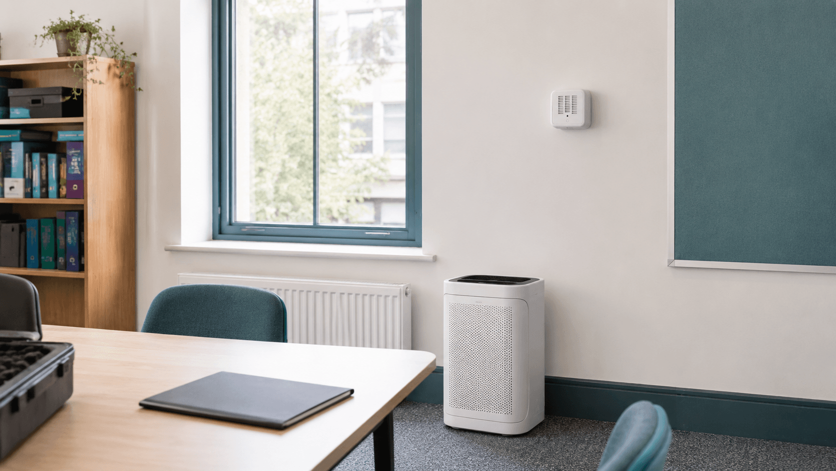 School room with a portable air purifier and wall-mounted air-quality sensor for intervention monitoring